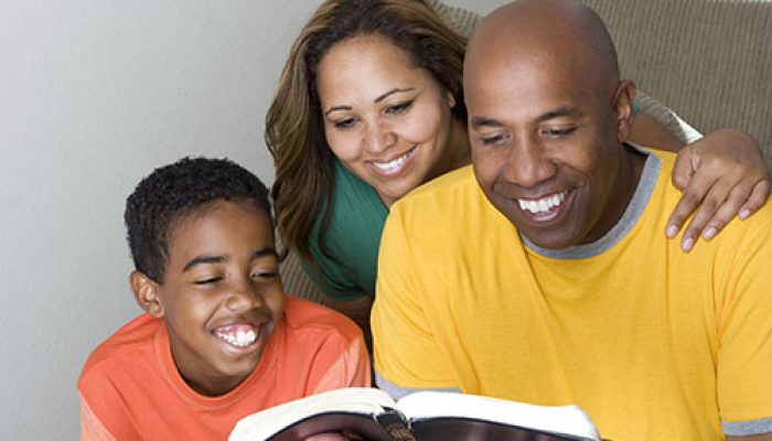 Happy African American family reading The Bible.